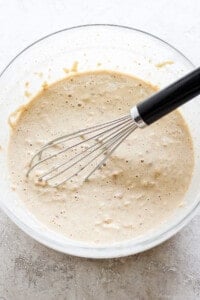 a bowl of batter with a whisk in it.