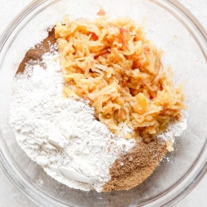 a bowl filled with flour, carrots, and other ingredients.