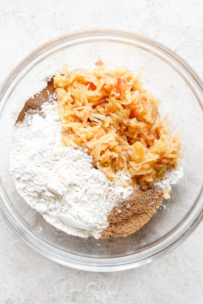 a bowl filled with flour, carrots, and other ingredients.