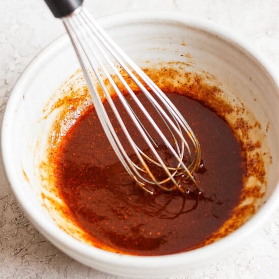 a bowl of sauce with a whisk in it.