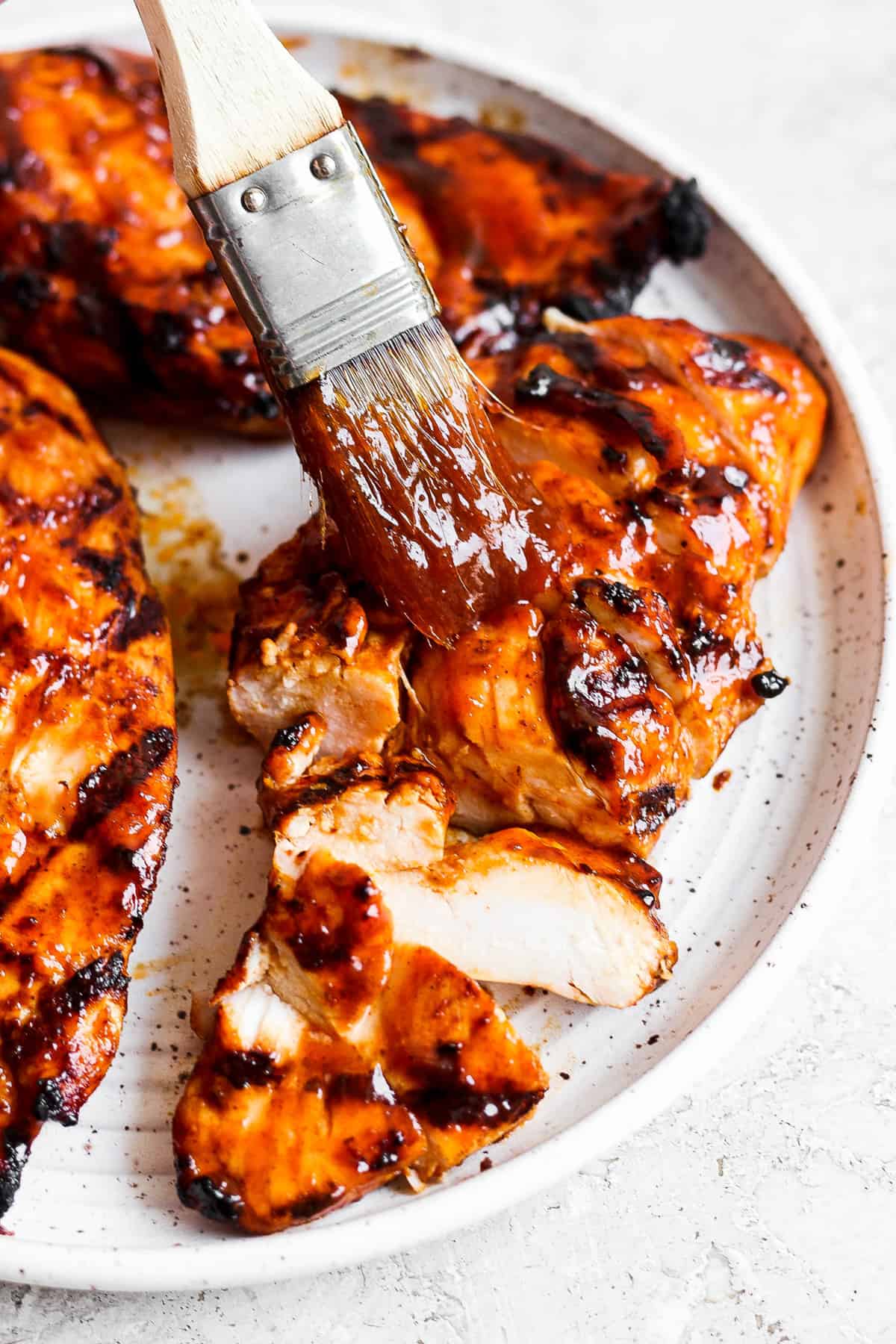 bbq chicken on a plate with a brush.
