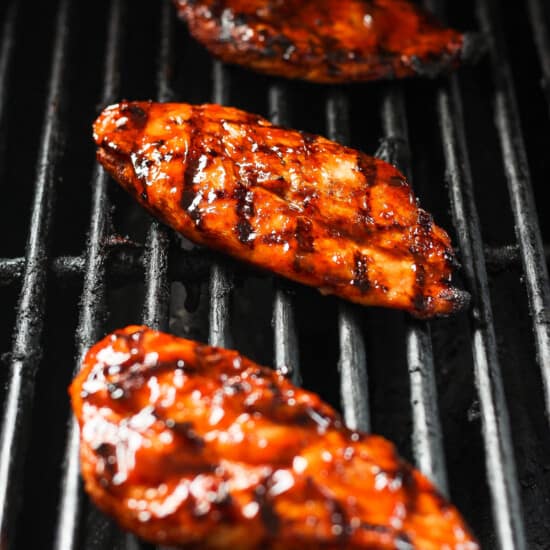 three grilled chicken breasts on a grill.
