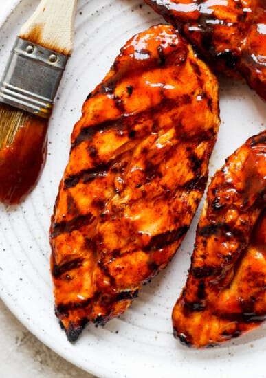 bbq grilled chicken on a white plate with a brush.