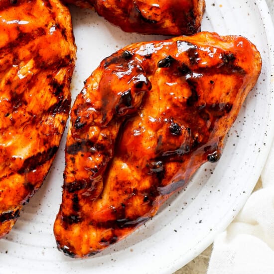 bbq chicken breasts on a white plate.