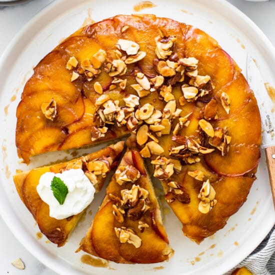 a peach upside down cake on a plate with a slice taken out.