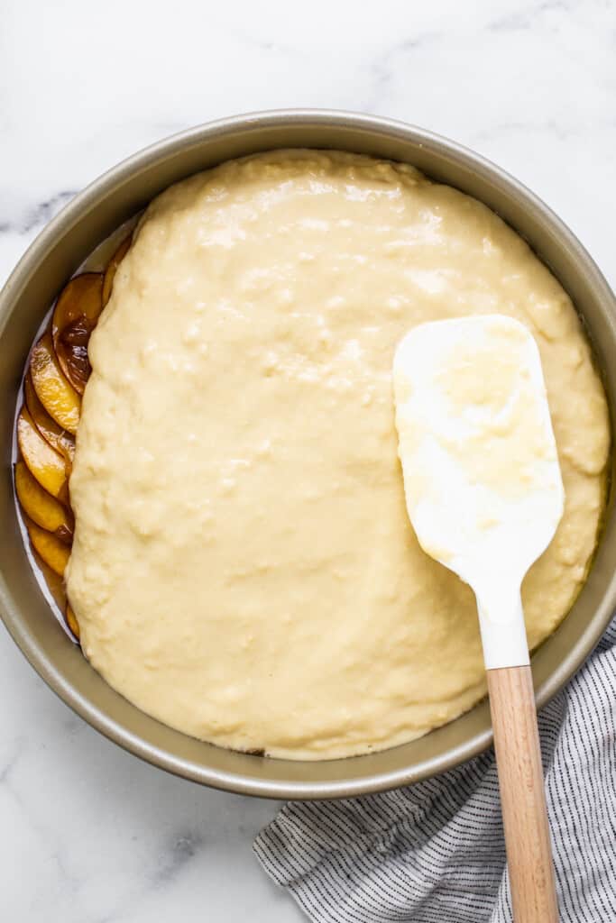 peach cake in a pan with a spatula.
