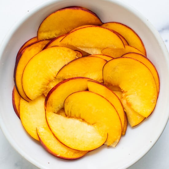 sliced peaches in a white bowl.