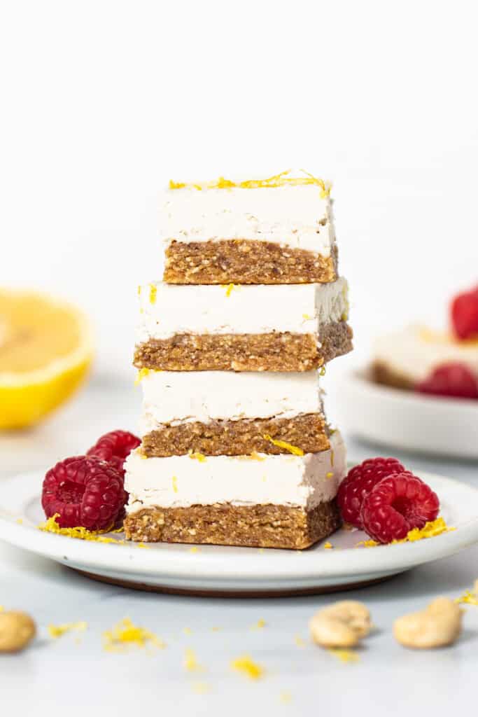a stack of lemon bars topped with raspberries and nuts.