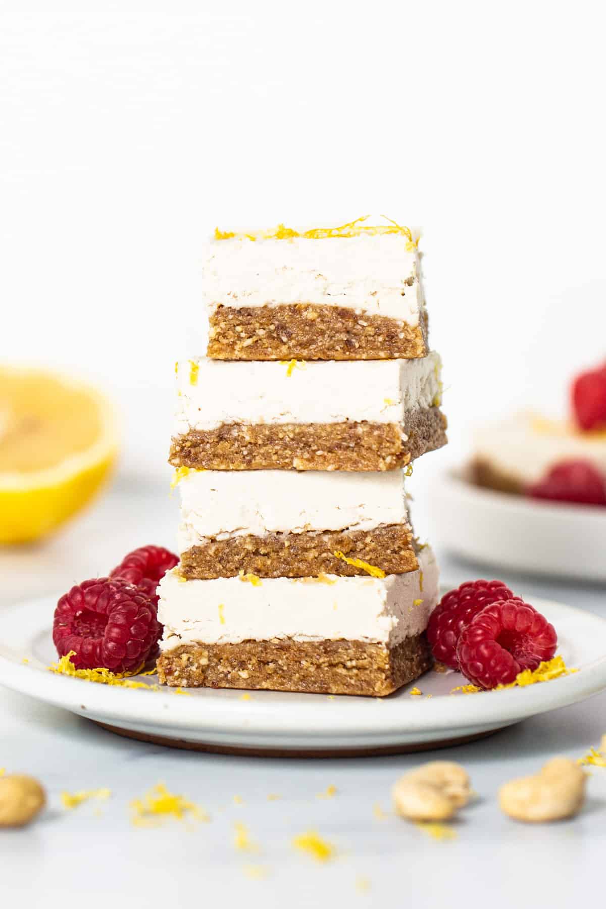 a stack of lemon bars topped with raspberries and nuts.