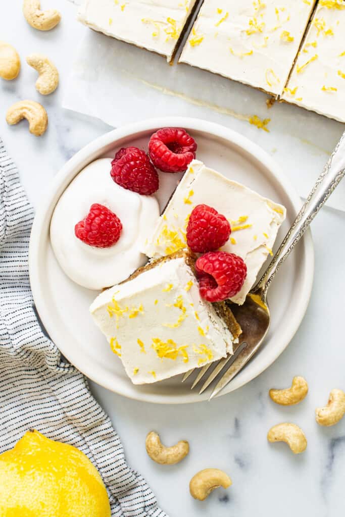 lemon bars with raspberries and cashews on a plate.