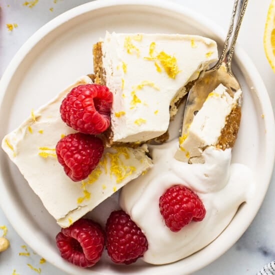a plate with lemon bars and raspberries on it.