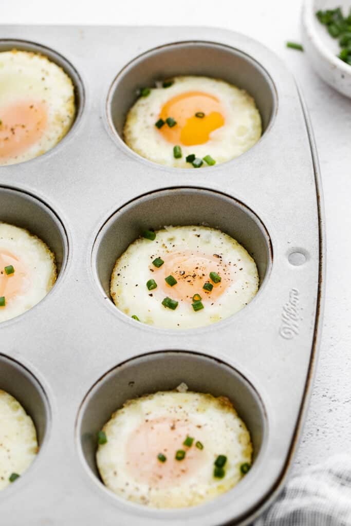 Instructions for baking eggs in the oven using a muffin tin, topped with fresh chives.