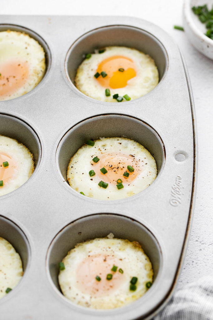 Instructions for baking eggs in the oven using a ،in tin, topped with fresh c،es.