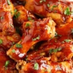 Crock pot chicken wings smothered in BBQ sauce neatly arranged on a plate.