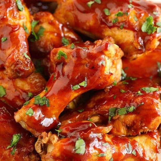 Crock pot chicken wings doused in BBQ sauce, neatly arranged on a plate.