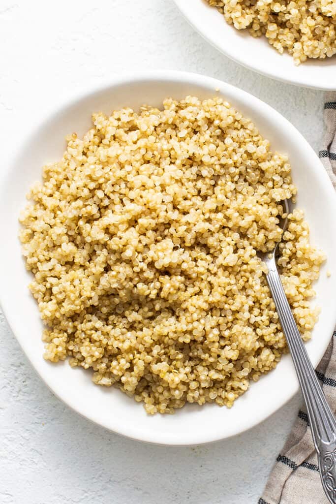 Cook quinoa in the microwave using a white bowl and a fork.
