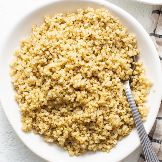 Cook quinoa in the microwave using a white bowl and spoon.