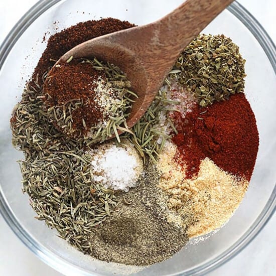 Spices in a bowl with a wooden spoon, perfect for flavorful turkey seasoning.