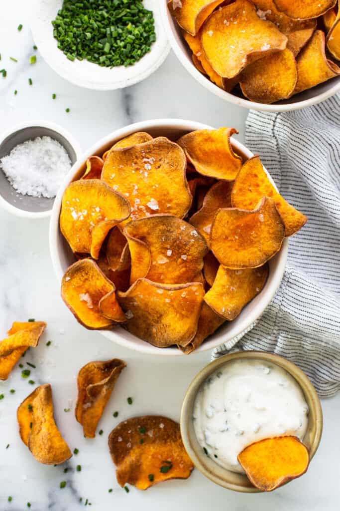 A bowl of sweet potato chips with dipping sauce.