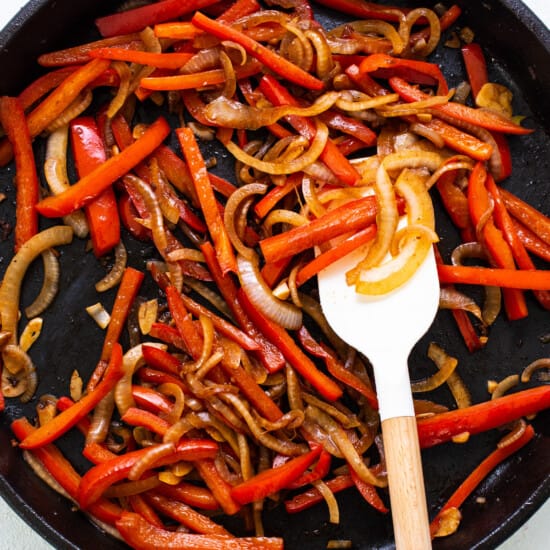 A skillet filled with red peppers and onions.
