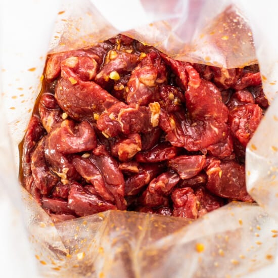 Roasted red peppers in a bag on a white plate.