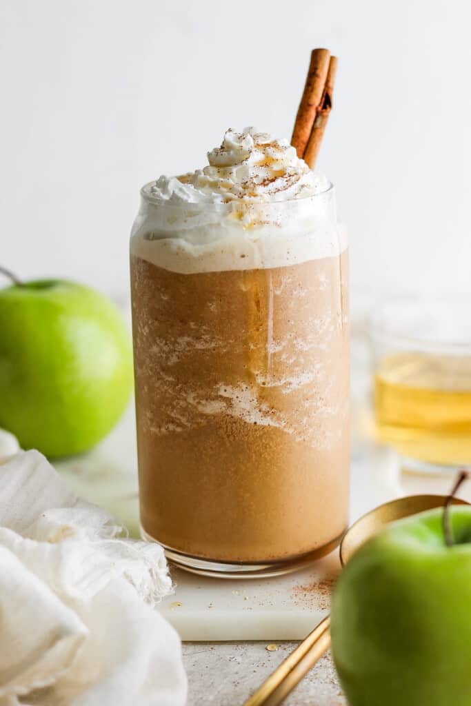 A pumpkin spice latte with whipped cream and apples.