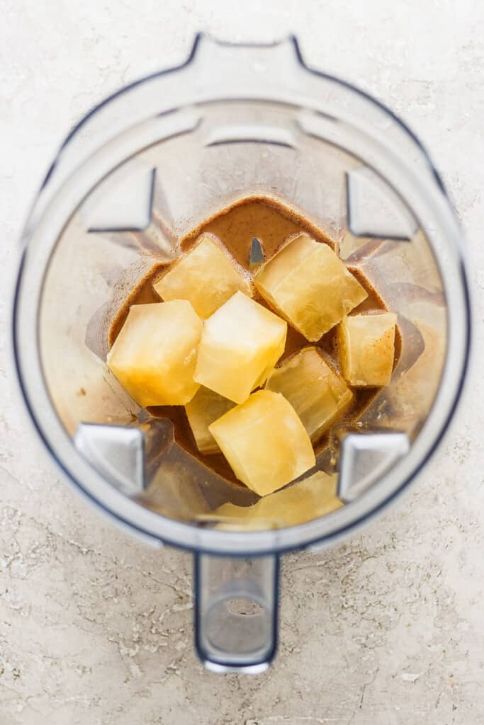 A blender with chunks of pineapple in it.