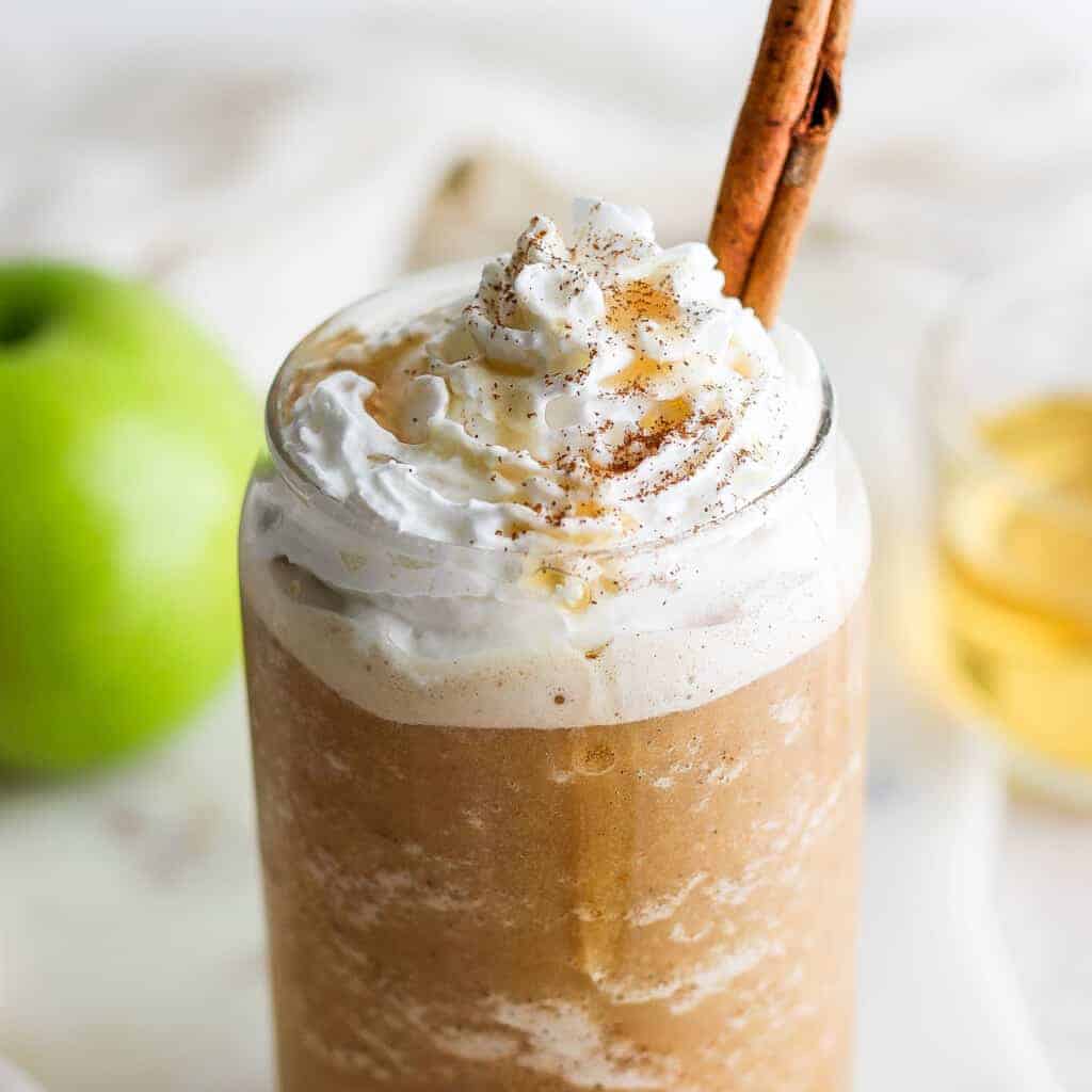 A mug with whipped pick  and a cinnamon stick.