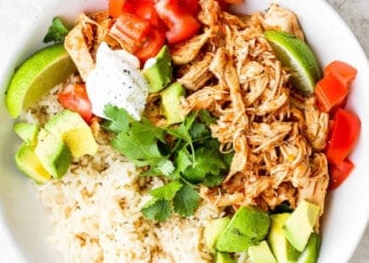 A bowl of rice and chicken with avocado and sour cream.