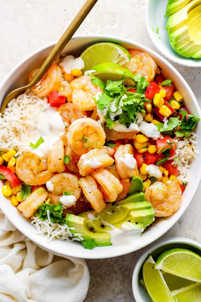 A white bowl with shrimp, corn and avocado.