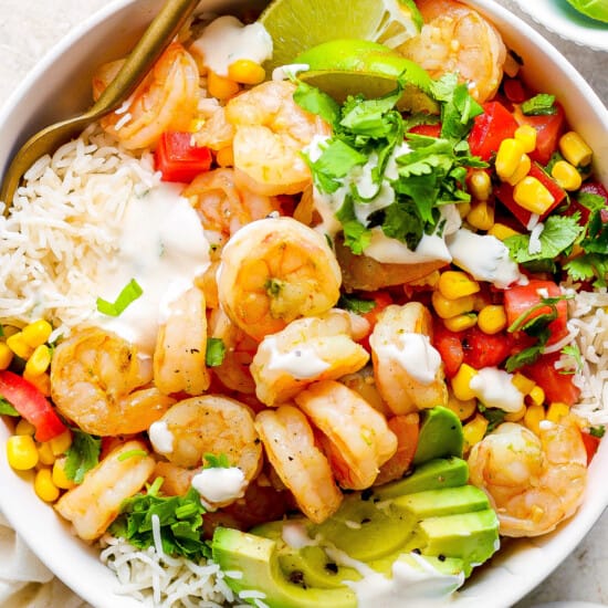 A white bowl with shrimp, rice and vegetables.