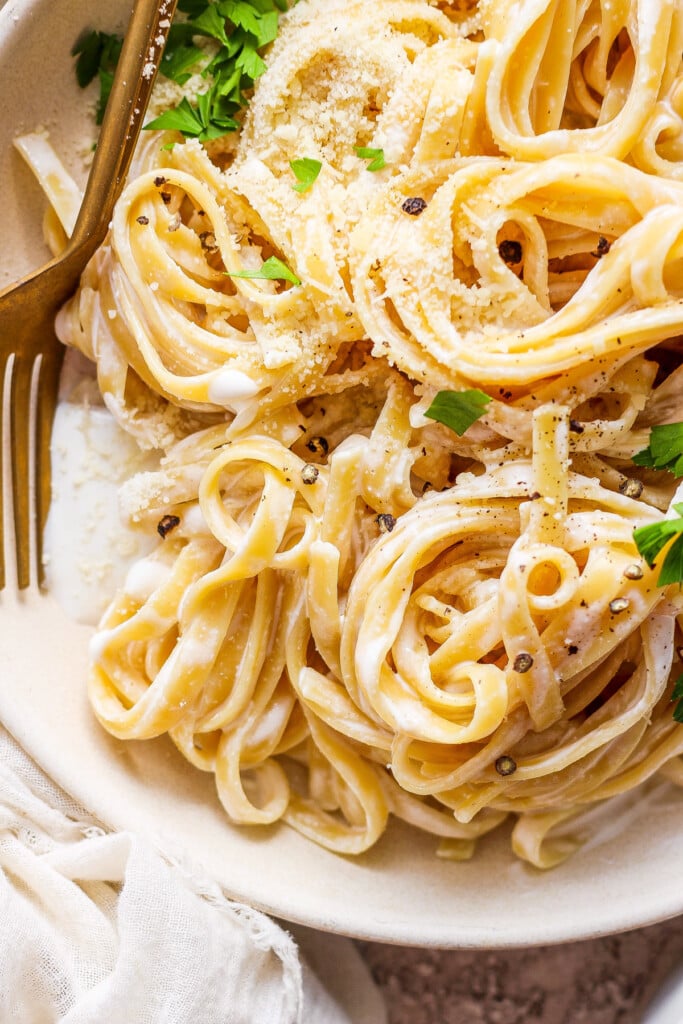 A bowl of pasta with parmesan cheese and parsley.