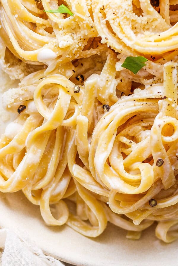 A plate of pasta with parmesan cheese and parsley.