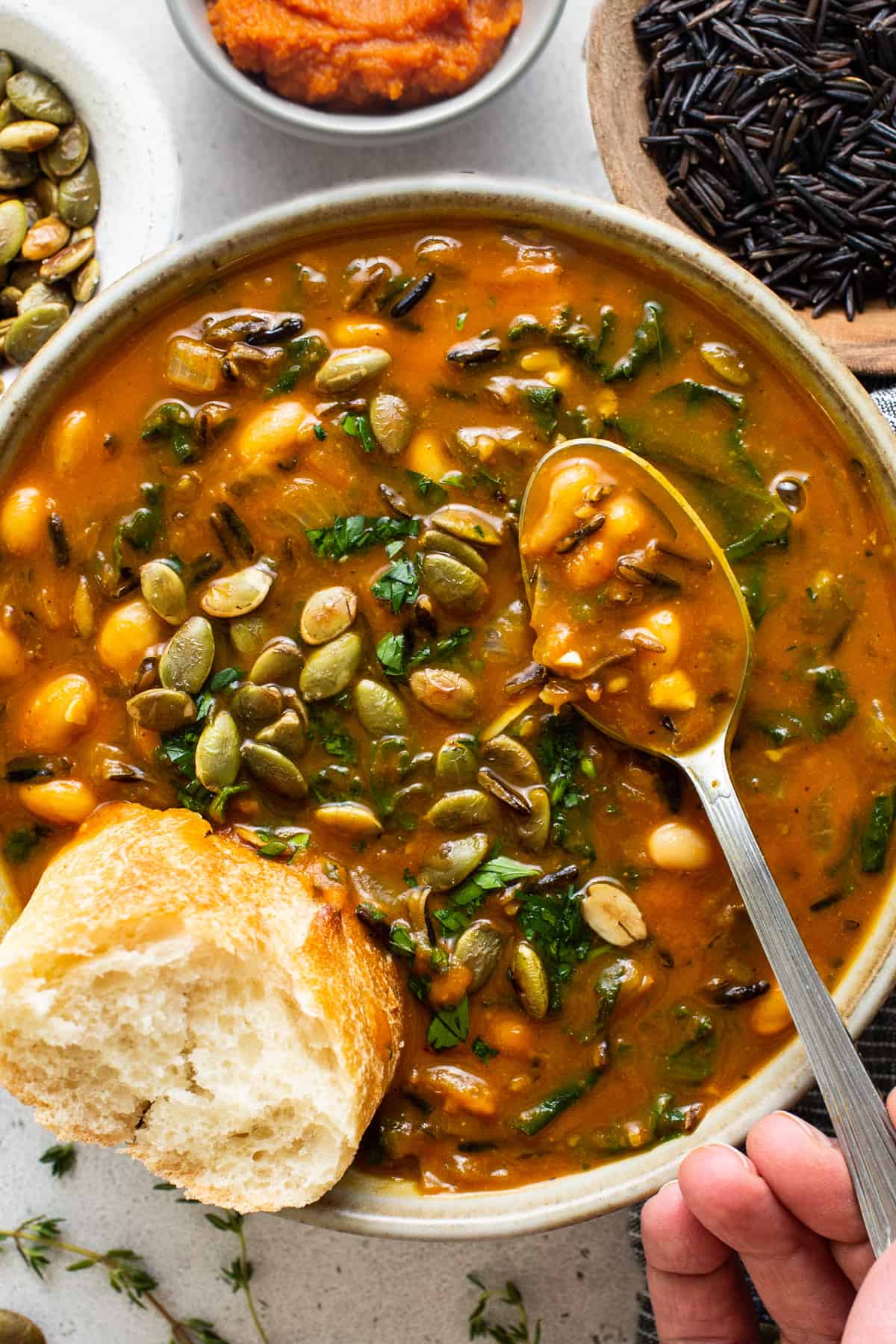 A bowl of soup with a hand holding a spoon.