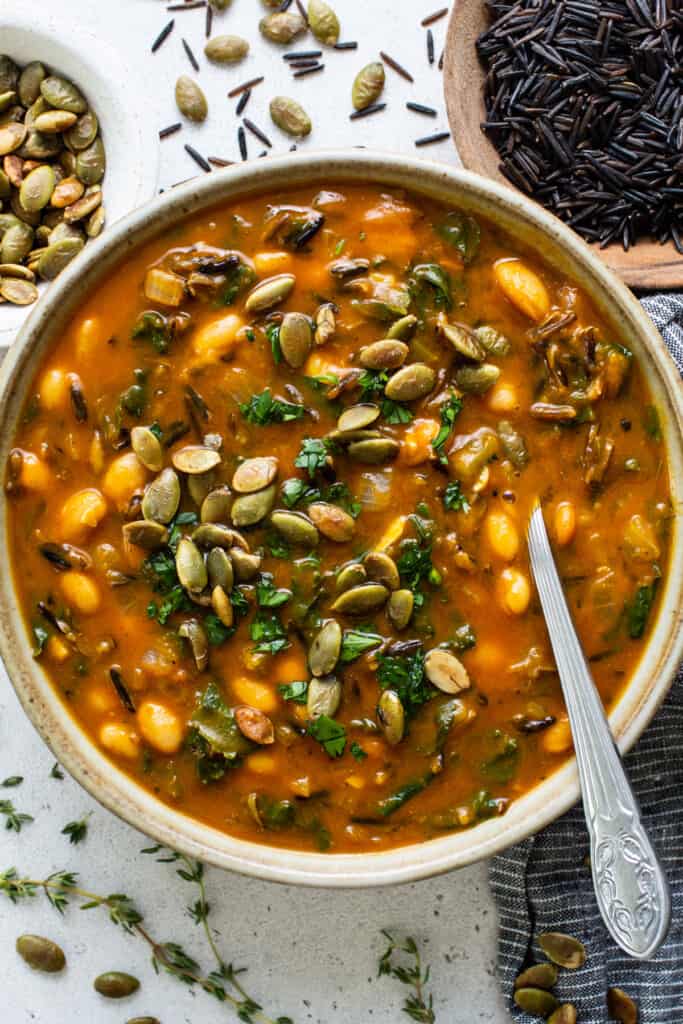 A bowl of soup with pumpkin seeds and beans.