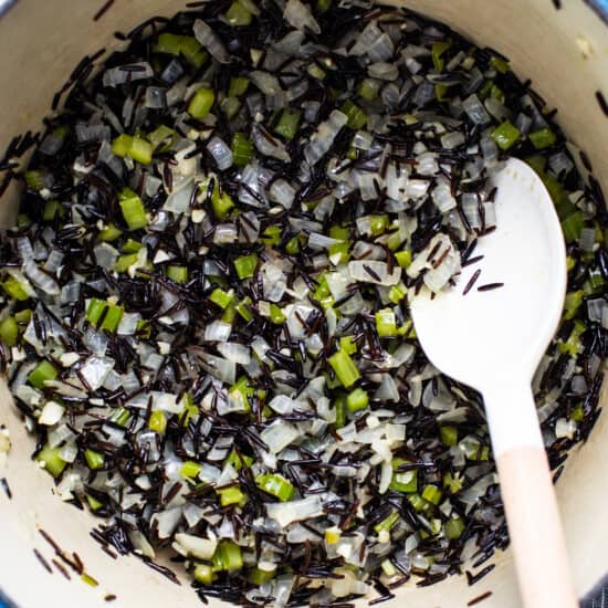 Black rice in a pot with a wooden spoon.