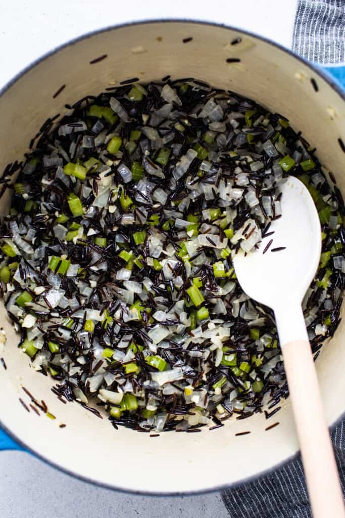 Black rice in a pot with a wooden spoon.