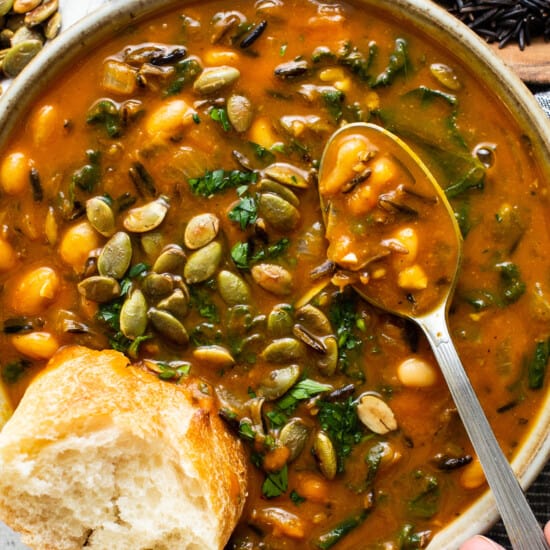 A bowl of soup with bread and spinach.