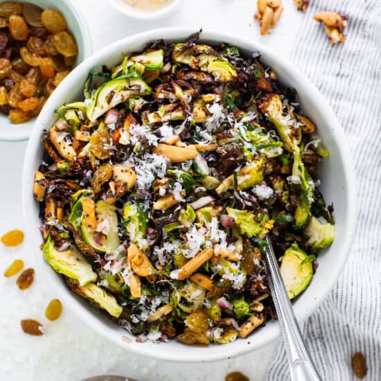 A bowl of brussels sprouts salad with nuts and raisins.