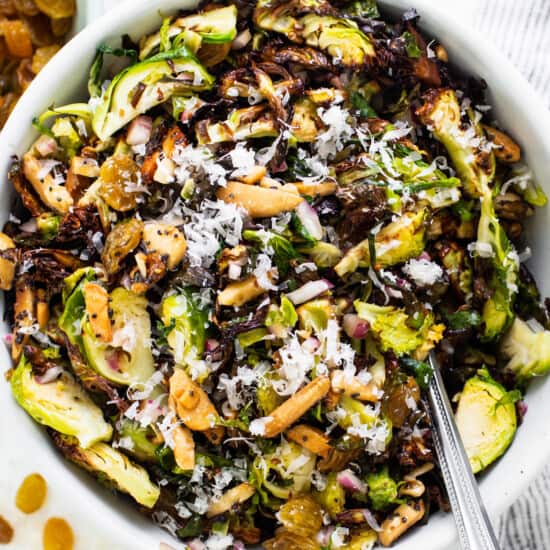 A bowl of brussels sprout salad with nuts and raisins.