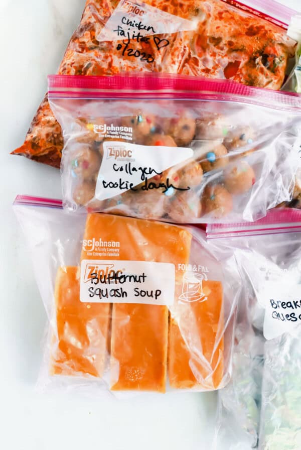 A variety of food in plastic bags on a white surface.