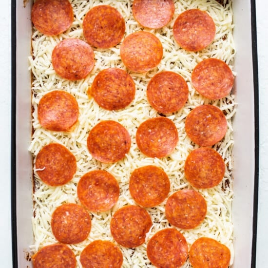 Pepperoni pizza in a baking dish with cheese on top.