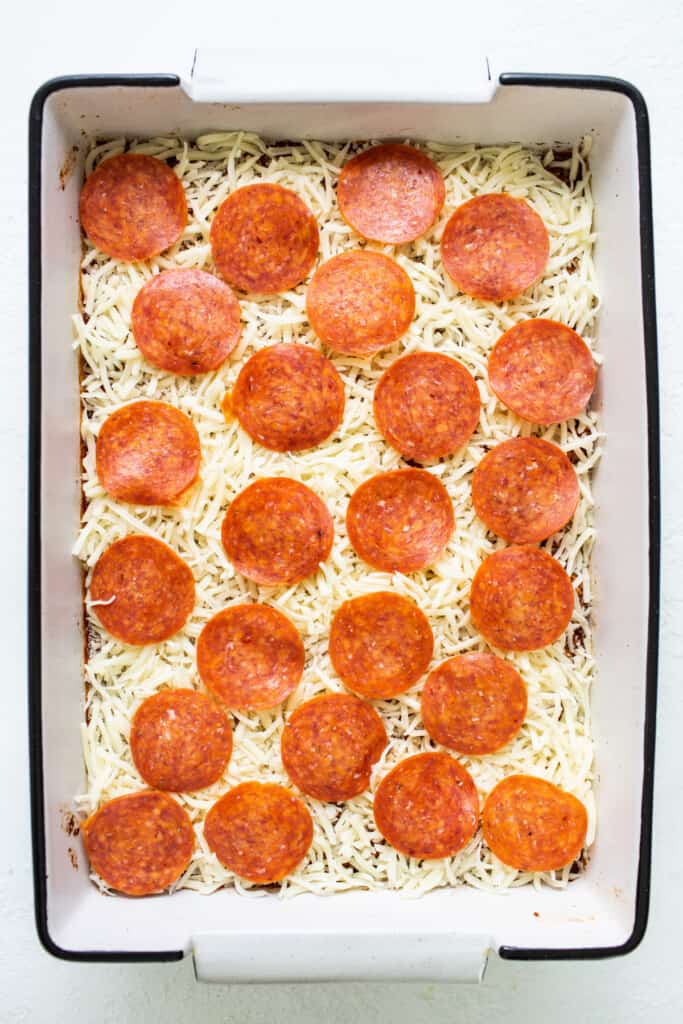 Pepperoni pizza in a baking dish with cheese on top.