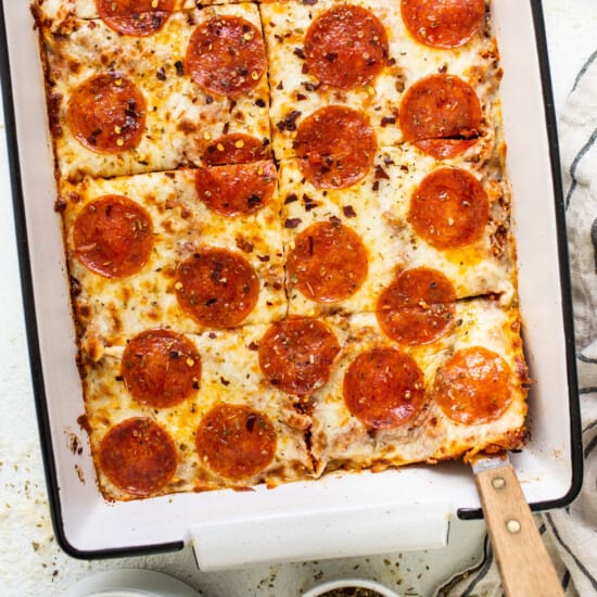 Pepperoni pizza in a baking dish with a spoon.