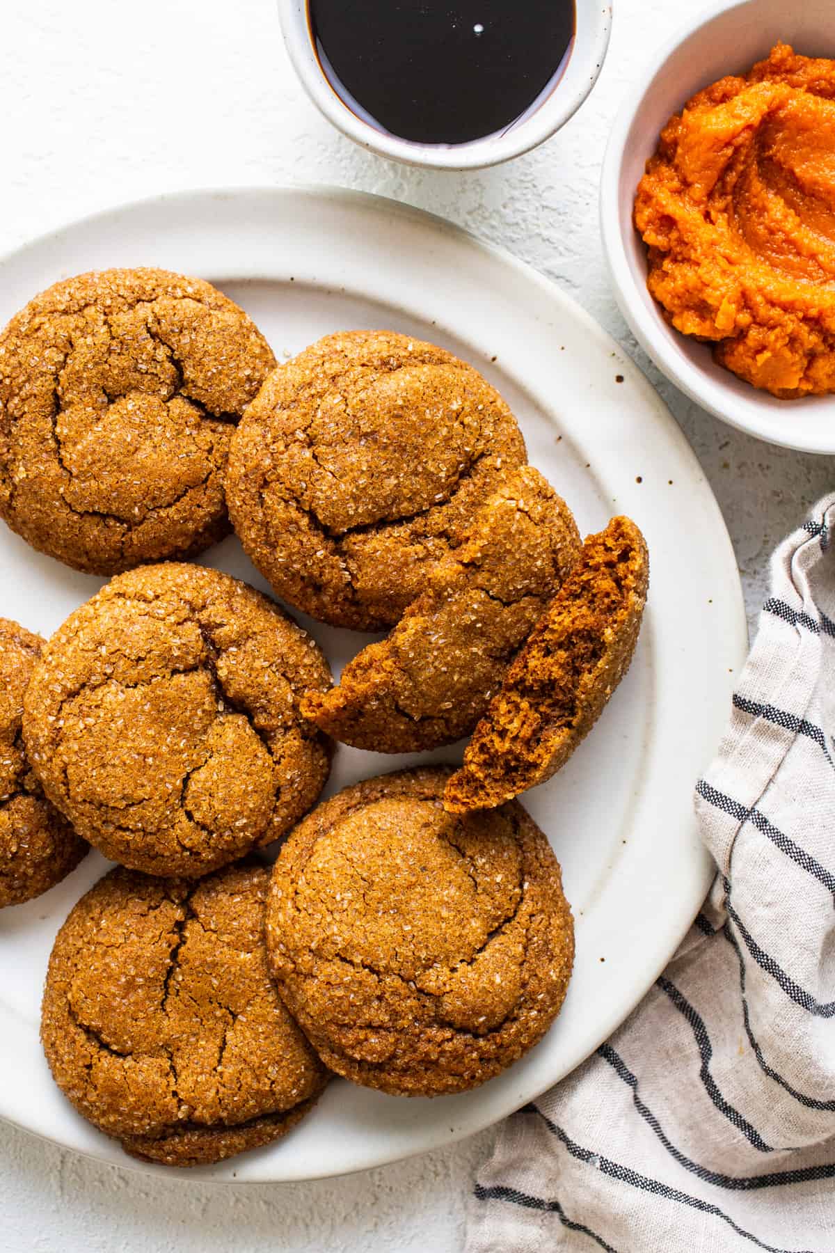 A plate of ginger cookies with a bite taken out of them.