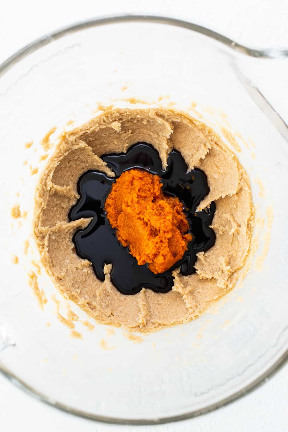 A glass bowl filled with a mixture of peanut butter and orange juice.