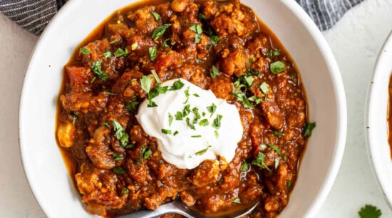 Two bowls of chili with sour cream and sour cream.