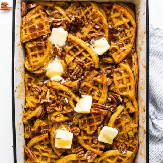 Pumpkin waffles in a baking dish with butter and pecans.