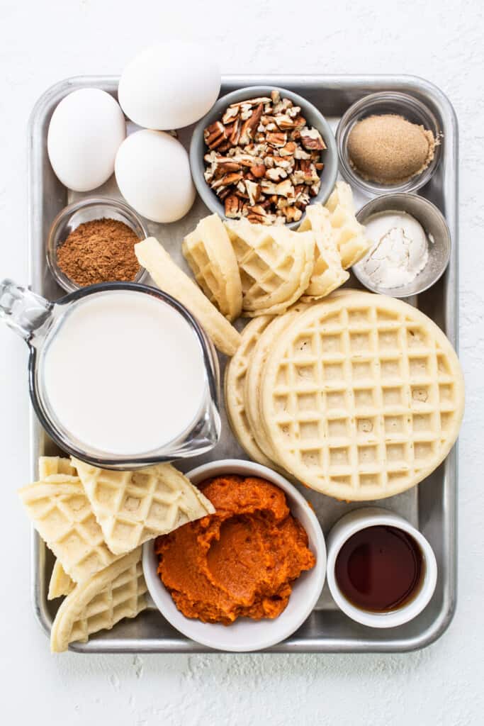 Waffles, eggs, milk and other ingredients on a tray.