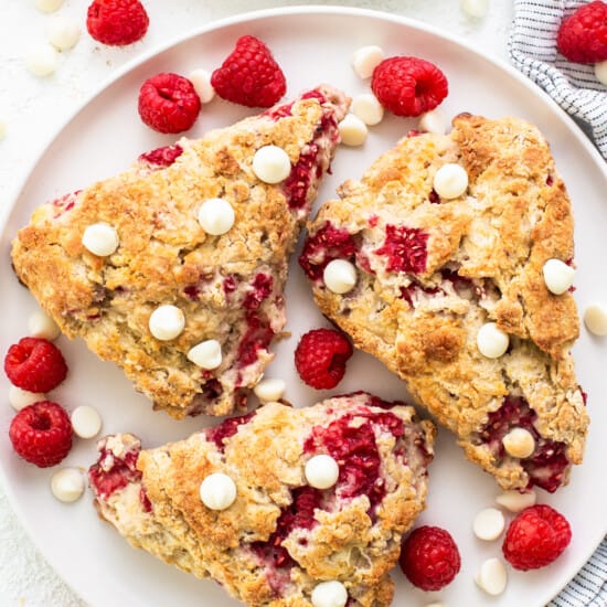 Raspberries and white chocolate scones on a white plate.